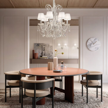 Classic Style Clear Crystal Chandelier A stylish dining room showcases a round table with four chairs under a Classic Style Clear Crystal Chandelier. The glowing fixture highlights the wooden ceiling, art-adorned walls, and marble clock, while a textured rug covers the floor and a console table with decor completes the scene.