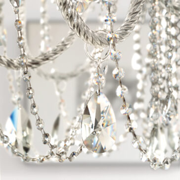 Close-up of the Classic Style Clear Crystal Chandelier, featuring clear faceted pendants and intricate chains. The sparkling crystals reflect light in multiple directions against a softly focused backdrop.