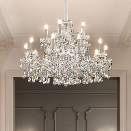 The Large Classic Style Crystal Chandelier with candle-shaped bulbs and ornate crystal drops hangs from a white ceiling, complemented by elegant decorative trim and classic wall paneling in the background.