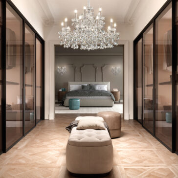Large Classic Style Crystal Chandelier A luxurious bedroom with a Large Classic Style Crystal Chandelier, an elegant four-poster bed, mirrored closets on both sides, parquet flooring, and plush ottomans in the foreground.