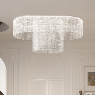 A luxurious Curved Cut Crystal Ceiling Light features two concentric circles of shimmering crystals, enhancing the room's opulent ambiance, alongside elegant molding and a framed painting on the wall.