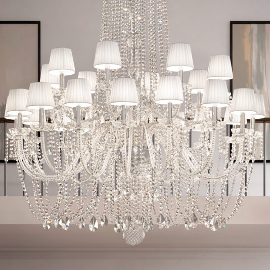 Large Tiered Crystal Chandelier The Tiered Classic Style Clear Crystal Chandelier features multiple arms with white lampshades, sparkling crystal beads, and pendants, adding elegance to any modern, well-lit room.