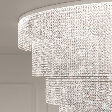 Large Tiered Cut Crystal Ceiling Light A close-up of the Large Oval Cut Crystal Ceiling Light displays cascading layers of sparkling crystals reflecting light in multiple directions against a softly blurred background, enhancing its shimmering, ornate chandelier design.