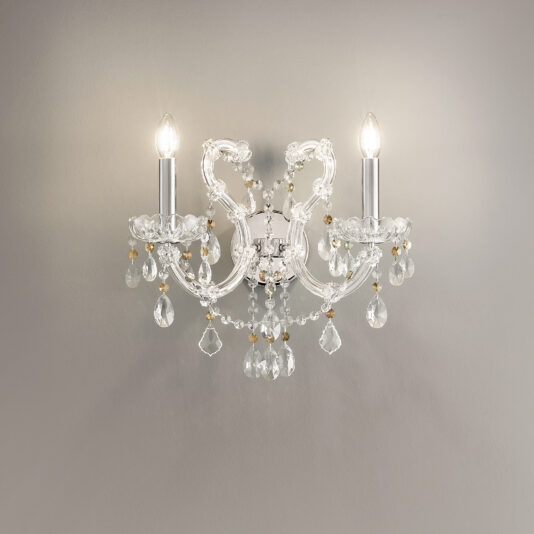 The Double Crystal Wall Light (Copy) showcases two candle-style bulbs, clear glass arms, and hanging crystal pendants, elegantly mounted on a light gray wall.