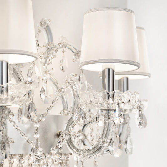 Close-up of the Classic Style Clear Crystal Chandelier, featuring hanging glass droplets and white fabric lampshades that reflect light for an elegant, luxurious look against a light-colored wall.