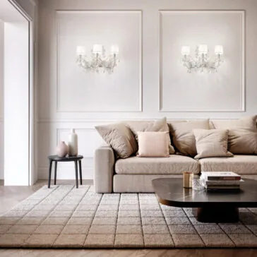 Silver Leaf Crystal Wall Light Modern living room with a beige sofa, neutral cushions, textured rug, dark coffee table, side table with vases, and two Classic Style Clear Crystal Wall Light (Copy) fixtures accenting the white paneled wall.