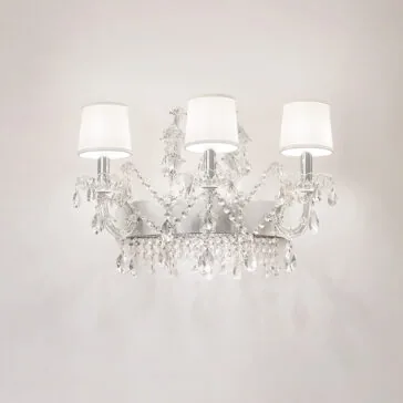 Silver Leaf Crystal Wall Light The Silver Leaf Crystal Wall Light features three arms with white shades, decorated with hanging crystal pendants and beads, beautifully displayed on a plain, light-colored wall.
