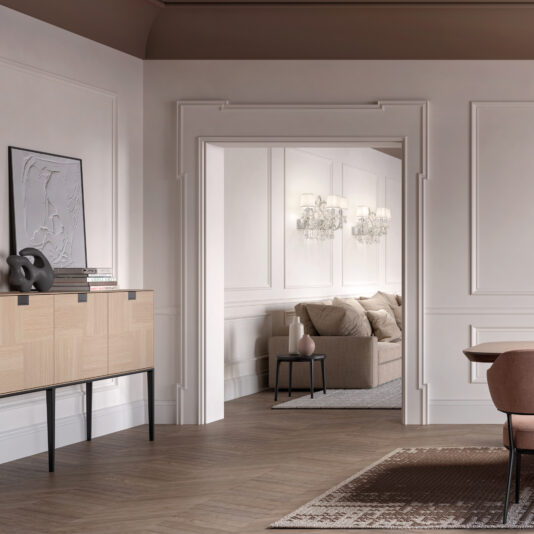 A modern living room with light wood furniture, a beige sofa, wall paneling, and elegant Classic Style Clear Crystal Wall Light (Copy) sconces. Neutral tones, contemporary decor, and a view into the adjacent seating area complete the space.