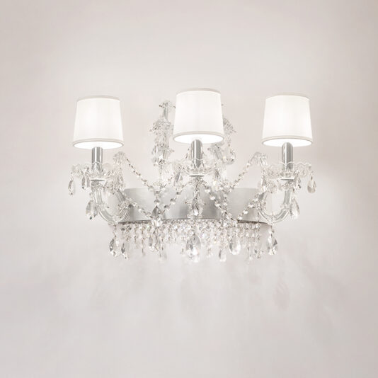 The Silver Leaf Crystal Wall Light features three arms with white shades, decorated with hanging crystal pendants and beads, beautifully displayed on a plain, light-colored wall.