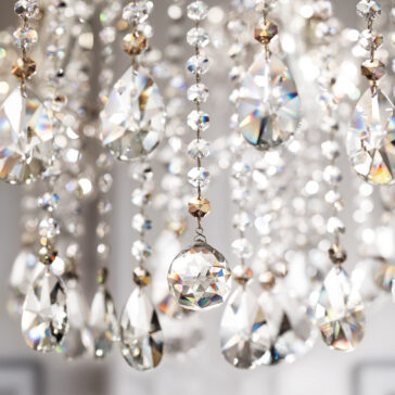 Close-up of hanging crystal prisms and beads on the Classic Style Empire Crystal Chandelier, reflecting light and casting rainbow patterns against a softly blurred background.