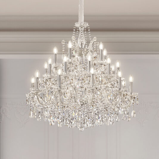 The Contemporary Crystal Drop Chandelier, featuring multiple tiers and candle-shaped bulbs, hangs from a white ceiling and sparkles in a bright, elegantly decorated room.