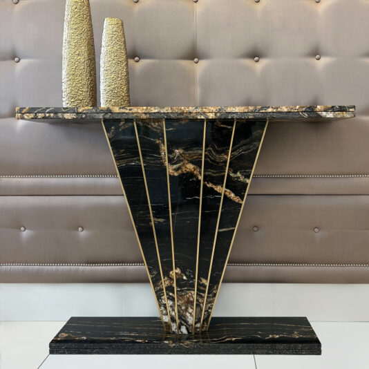 The Exclusive Art Deco Style Console Table features black marble with gold veining, a fan-shaped base, and two textured gold vases atop, all set before a tufted beige wall.