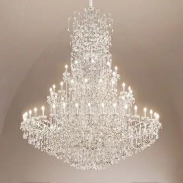 Grand Tiered Crystal Empire Chandelier The Grand Statement Tiered Crystal Chandelier hangs from the ceiling, its many lights illuminating sparkling crystals and creating an elegant display against a plain, light-colored background.