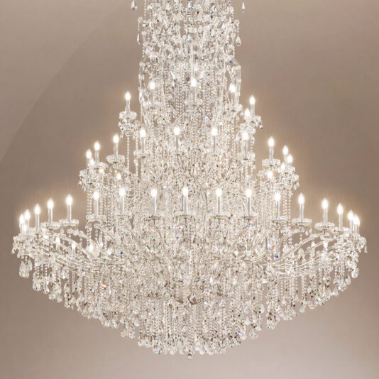 Grand Tiered Crystal Empire Chandelier The Grand Statement Tiered Crystal Chandelier, featuring multiple tiers and candle-style bulbs, hangs elegantly from the ceiling against a neutral backdrop.