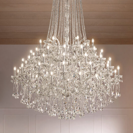 The Grand Tiered Crystal Empire Chandelier (Copy) hangs from a wooden ceiling, sparkling with glass prisms and decorative drops above an elegantly lit room.