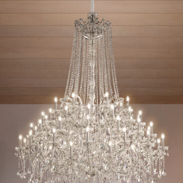 The Grand Tiered Crystal Empire Chandelier (Copy) features multiple lit bulbs and cascading crystal strands, elegantly suspended from a wooden ceiling.