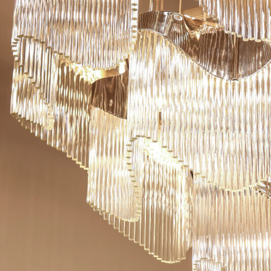 Contemporary Wavy Tiered Chandelier Close-up of the Contemporary Wavy Tiered Chandelier, with cascading glass prisms that sparkle beautifully against a beige background.
