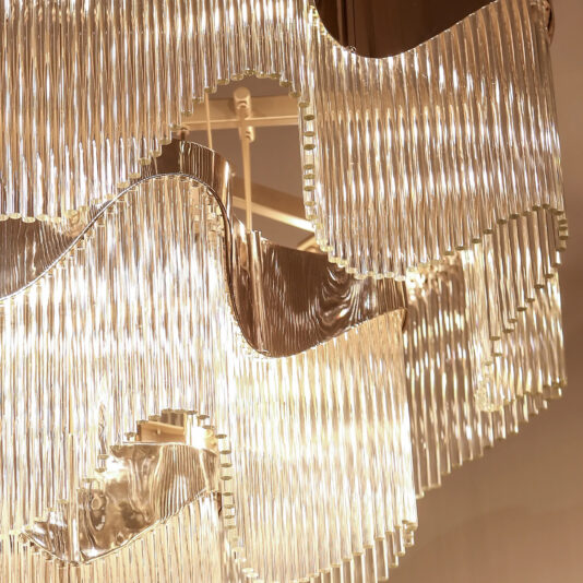 Contemporary Wavy Tiered Chandelier Close-up of the Contemporary Wavy Tiered Chandelier, featuring layers of sparkling clear glass pieces that reflect a warm, golden glow.
