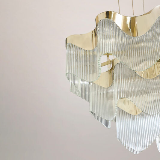 Contemporary Wavy Tiered Chandelier The Contemporary Wavy Tiered Chandelier, featuring gold and glass accents, hangs from the ceiling against a simple, light background.