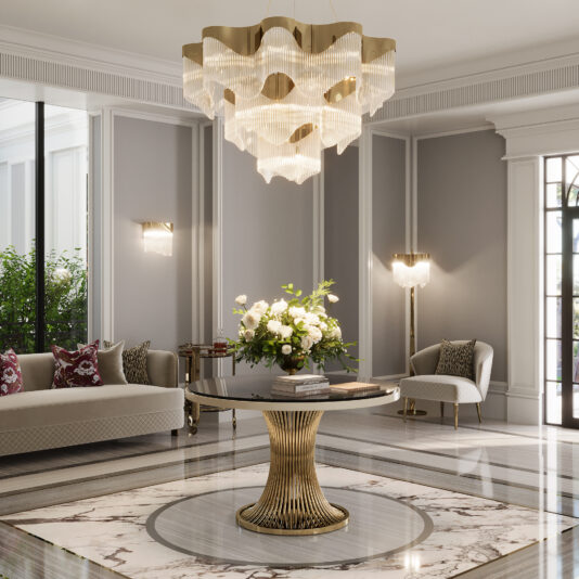 Round Lacquered Contemporary Dining Table Elegant foyer with a Round Marble Contemporary Dining Table (Copy) topped by a floral arrangement, gold chandelier overhead, gray walls with white trim, plush sofas, and large windows for natural light.