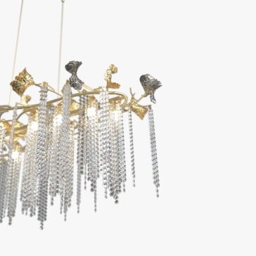 Contemporary Leaf Chandelier With Crystal Drops The Contemporary Wavy Tiered Chandelier (Copy) features cascading crystal strands and decorative gold and silver leaves, set against a plain white background.