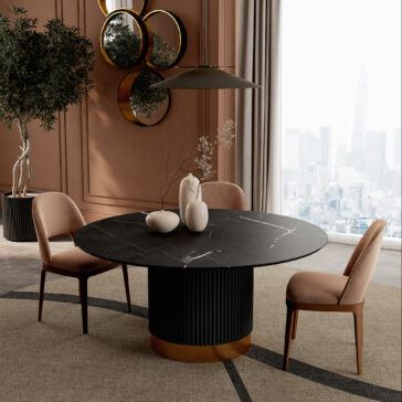A modern dining room featuring a Round Contemporary Lacquered Dining Table, three pink velvet chairs, decorative vases, a large potted plant, and circular mirrors on a brown wall; city view seen through tall windows.