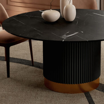 The Round Contemporary Lacquered Dining Table (Copy) in black marble has a fluted cylindrical base with a gold-edged bottom, decorated with white ceramic vases and set on a beige textured geometric-patterned carpet.