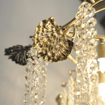 Close-up of the Contemporary Leaf Chandelier With Crystal Drops, showcasing metallic leaf-shaped accents, sparkling crystal bead strands, and a warm illuminated glow.