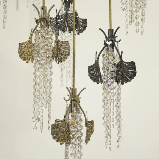 Multiple Large Leaf Chandelier With Crystal Drops (Copy) fixtures, with gold and dark metal leaves and cascading crystals, hang against a light background for a luxurious, elegant look.