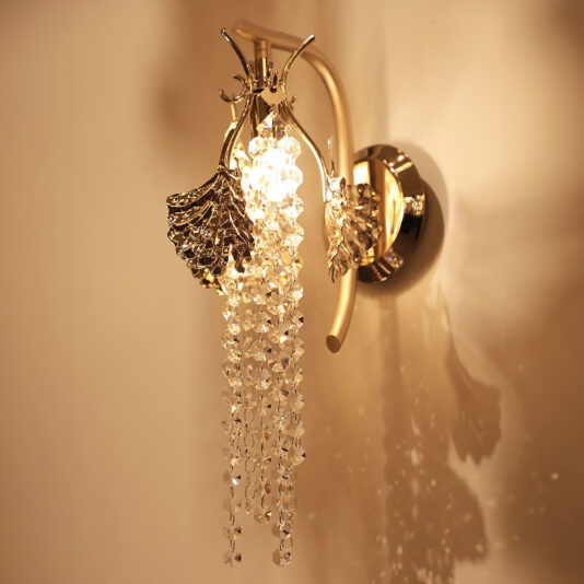 Leaf Wall Light With Crystal Drops The Leaf Wall Light With Crystal Drops features intricate leaf designs and hanging crystals, casting warm light and elegant shadows on the wall when lit.