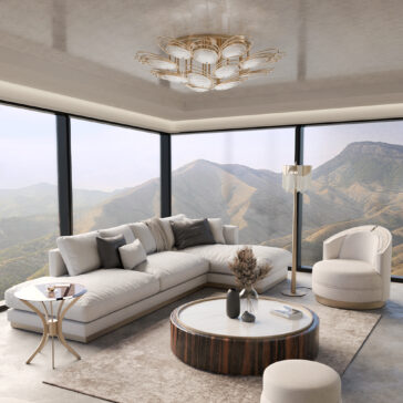 A modern living room with floor-to-ceiling windows and mountain views features a white sectional, round coffee table, armchair, and a Modern Stairwell Chandelier Inspired By The Sea (Copy) among neutral-toned decorative accents.