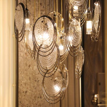 Modern Stairwell Chandelier Inspired By The Sea The Modern Round Chandelier Inspired By The Sea (Copy) features multiple glass discs and exposed bulbs, creating artistic reflections on neutral walls with its contemporary, sea-inspired design.