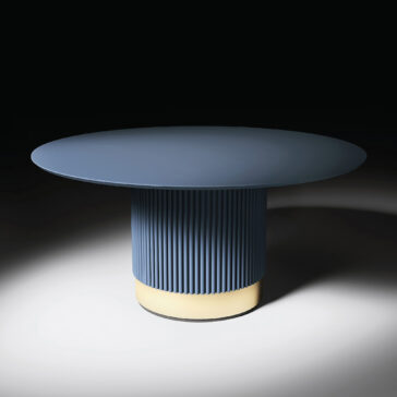 The Round Contemporary Lacquered Dining Table features a smooth round top and a fluted cylindrical base with a glowing light near the bottom, shown against a dark background for a modern look.