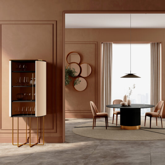 A modern dining room with earth-toned walls, a round black table, four beige chairs, a hanging pendant light, a Contemporary Lacquered Cabinet (Copy) displaying glassware, wall art, a plant, and large windows with sheer curtains.