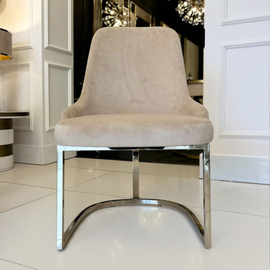 The Contemporary Two-Tone Leather Dining Chair with a chrome base stands on glossy white tiles in a bright, stylish room with white paneled walls and chic décor.
