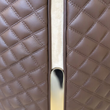 Contemporary Two-Tone Leather Dining Chair Close-up of the Contemporary Two-Tone Leather Dining Chair, showcasing brown quilted upholstery and a shiny metallic handle with a beige vertical accent in the center.