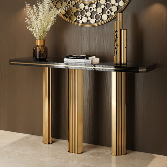 The Modern Lacquered Demi Console (Copy) with a black top and three gold legs stands against a brown wall, adorned with a brown vase of white flowers, stacked books, and a tall gold decorative piece.