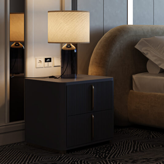 The Modern Ribbed Lacquered Bedside Drawers hold a black lamp, electrical outlets, and a digital clock next to a beige upholstered bed in a stylishly dim bedroom.