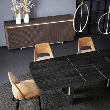 Modern Veneered Ribbed Sideboard A modern dining room with a dark wood table, four tan velvet chairs, a Modern Lacquered Sideboard with white vases and dried flowers, gold pendant lights, all on a gray rug against gray walls.