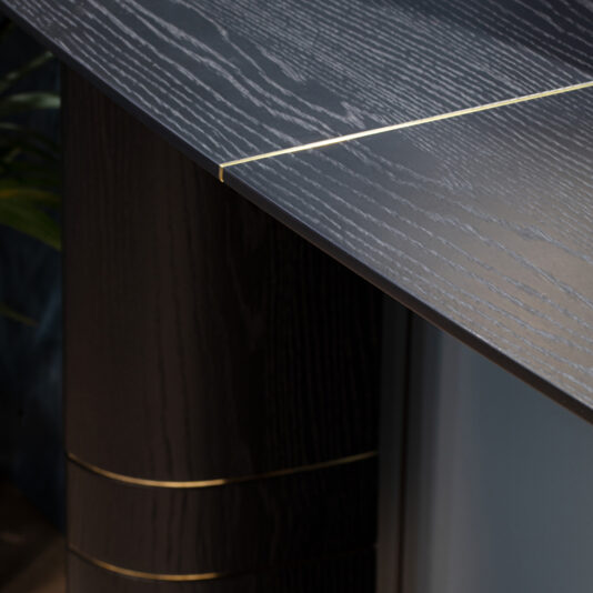 Close-up of a modern dark wood table with textured grain and thin gold accents, showcasing the refined style of the Wall Mounted Contemporary Console Table.