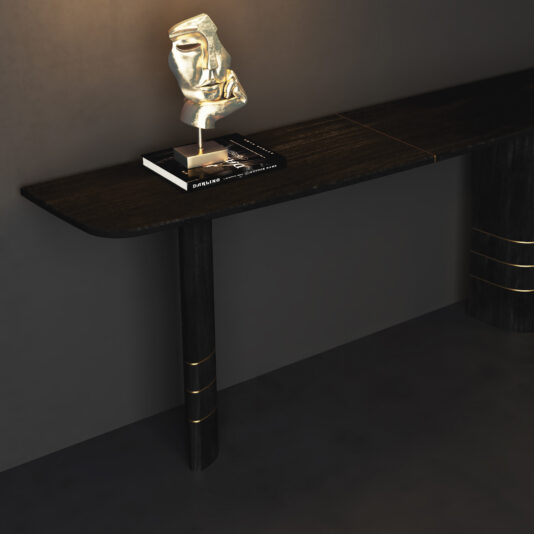 A Wall Mounted Contemporary Console Table with gold accents stands against a dark wall. Beside it, a round glass dining table adds elegance, while a metallic abstract face sculpture sits on two stacked books.