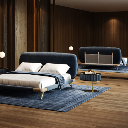 Contemporary High End Italian Bed A modern bedroom highlights the Contemporary High-End Italian Bed in dark blue upholstery, complemented by a matching rug, round bedside table, pendant lights, wood-panelled walls, and a large mirror reflecting the décor.