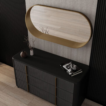 A black console table holds a brown vase with twigs and a magazine. Next to it, a geometric chaise longue sits beneath the Contemporary Pill Wall Mirror, which reflects the light wooden floor and textured walls.