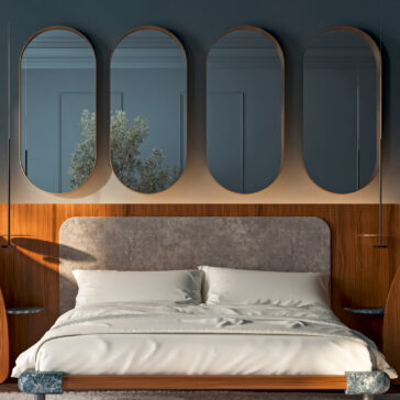 A modern bedroom features a neatly made bed with white bedding, a grey upholstered headboard, wooden paneling, four oval mirrors, and the Contemporary Geometric Chaise Longue (Copy), while soft lighting warms the space.