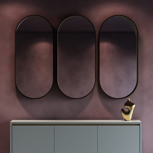 Contemporary Pill Wall Mirror Three oval mirrors hang on a mauve wall above a light gray cabinet, enhanced by a shiny gold abstract sculpture and the Contemporary Geometric Chaise Longue (Copy), creating a modern, elegant look.