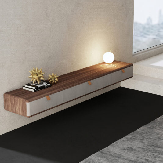The Contemporary Veneered Floating Sideboard holds books, two gold accents, and a glowing round lamp, and is mounted on a light wall by a large window with city views.