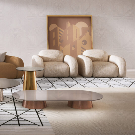 Contemporary Italian Armchair Modern living room featuring a contemporary Italian armchair in cream with a matching rounded armchair, geometric wall art, two metallic-base coffee tables on patterned rugs, and textured, light-coloured wallpaper in the background.