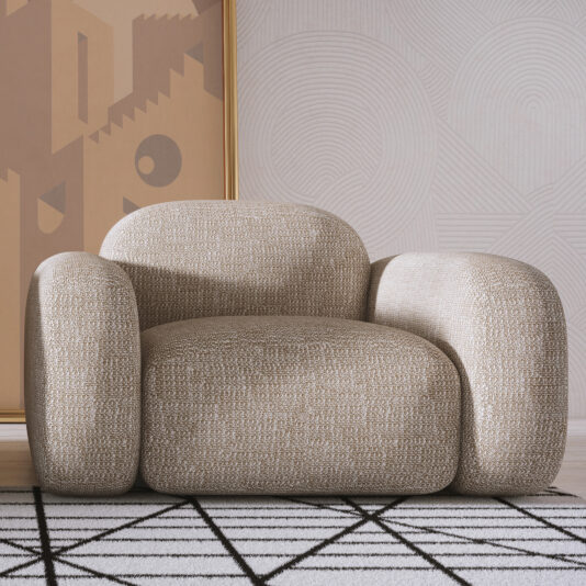 Contemporary Italian Armchair The Contemporary Italian Armchair, in modern beige with rounded, textured cushions, sits on a geometric black-and-white rug. A framed abstract artwork leans against a wall adorned with subtle circular patterns behind the chair.