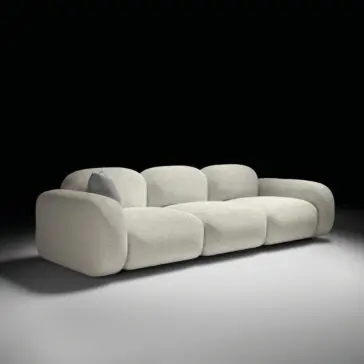 Contemporary Italian Sofa The Contemporary Italian Sofa features a modern, light grey plush design with rounded edges and a darker grey cushion, highlighted against a dark backdrop with a soft spotlight.