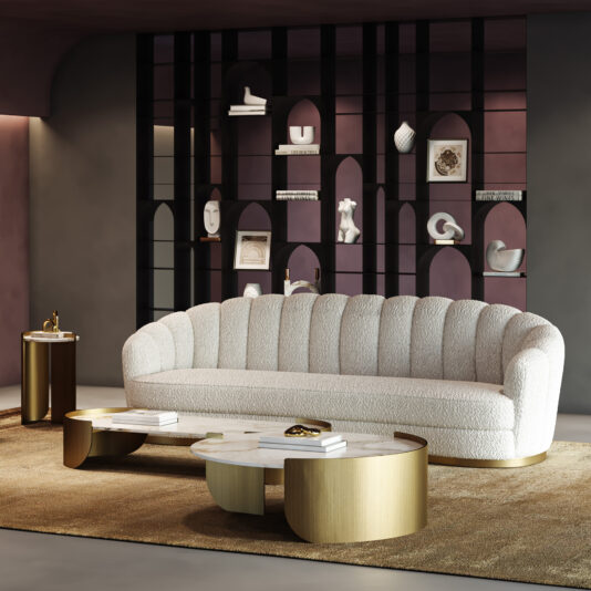 Contemporary Faux Marble Coffee Tables A modern living room with a curved, white textured sofa, Contemporary Marble Coffee Tables with gold accents, a side table, and a brown rug. In the background is a dark arched shelving unit decorated with ornaments.